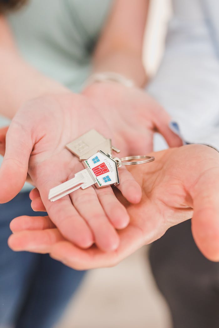 Close-up of hands holding a key with a house-shaped keychain, symbolizing new beginnings.